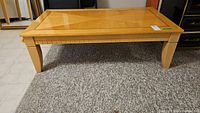 Front view of rectangular wood coffee table showing tapered legs and wood finish with some flaws.