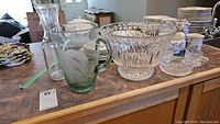 Overview photo showing crystal bowl, green glass cream and sugar set, clear glass jug and wine carafe.
