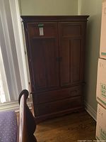 Front and side view of wood armoire showing paneled doors, drawers, and traditional design