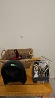 Overall view showing Honeywell fan, Conair hair dryer inside basket, and metal box with hand tools
