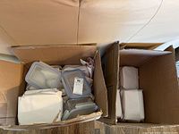Two open cardboard boxes filled with food storage containers in various sizes, wrapped in paper for protection.