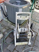 Front view of weathered plastic hose caddy with handle and spool partially wound with hose.