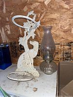 Oil lamp and vintage painted metal wall hanger with two circular pot holders in a shed