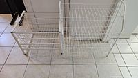 Two white wire storage racks shown side by side on tiled floor.