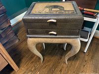 Front view of decorative wood box on curved leg wood table showing top print and handles.