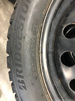 Close-up of sidewall showing Bridgestone branding, DOT code and rim edge