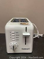 White Cuisinart CPT-122C compact two-slice toaster showing front controls including lever, buttons for bagel, defrost, reheat, and browning dial with Cuisinart branding on the base.