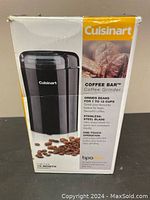 Front of retail box showing product image, brand, and features like grinding 1 to 12 cups, stainless steel blade, one-touch operation, BPA free