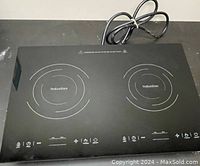 Front view of the black dual burner induction cooktop showing induction zones and touch control panel.