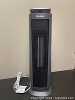 Front view of Pelonis grey tower heater showing mesh front grille and white cord coiled at base.