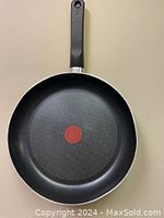T-Fal 30cm non-stick frying pan with black handle, showing the cooking surface with red Thermo-Spot heat indicator and slight dent on the side.