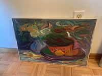 Full view of the framed painting on the floor showing still life with a vase and fruit plate with visible brush strokes and signature colors.