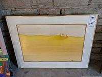 Full view of framed watercolor leaning against stone wall