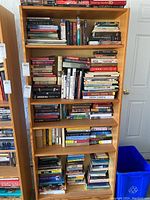 Front view of wooden bookcase filled with various books on six shelves.