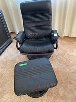 Full view of black swivel chair and ottoman on carpeted floor