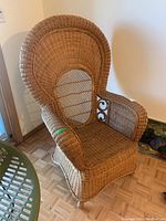 Side angle showing high back wicker arm chair, intricate armrest detailing, and parquet wood floor.