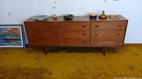 Full front view of teak veneer dresser on yellow carpet