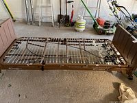 Full view of medical bed frame with brown plastic head and foot boards, on casters, coil spring base visible.