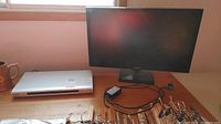 Samsung 27-inch monitor on desk next to silver Sony DVD player with power cable and accessories visible.