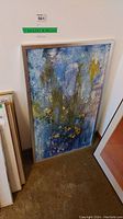 Full view of the framed blue and yellow textured abstract painting leaning against a wall.