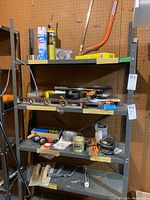Shelf setup with various hand tools including levels, clamps, and small hardware items