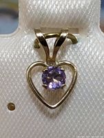 Front view of 10K yellow gold heart shaped pendant with amethyst stone showing gemstone color and setting.