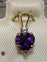 Close-up image of the pendant showing the heart-shaped deep purple amethyst and the white sapphire above it, mounted in 10K gold.