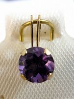 Front close-up showing the round faceted purple amethyst held by four gold prongs on a 10K gold pendant.