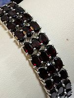 Close up image showing the oval shaped deep red garnets set in sterling silver prongs on the bracelet.