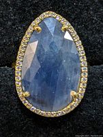 Top-down view of pear-shaped blue sapphire center with surrounding halo on black background