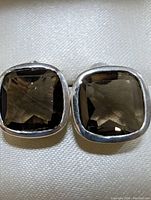 Close-up photo of the front of one earring showing square faceted smokey quartz stone set in a rounded sterling silver bezel.