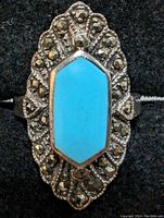 Front view of sterling silver ring showing hexagonal turquoise stone and marcasite decoration on black background.