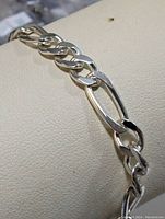Close-up of bracelet links showing alternating large elongated oval links and smaller curb links with polished finish.