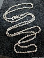 Full view of sterling silver box chain necklace laid out on a dark surface, showing the chain links and lobster clasp closure.