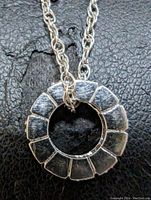 Close-up photo of the circular sterling silver pendant with segmented design showing polished silver sections.