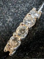 Close-up photo showing five clear round cubic zirconia stones set in sterling silver band, detail of prong settings and stone clarity