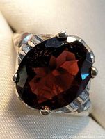 Close-up front view of the sterling silver ring with large oval garnet gemstone showing rich red color and prong setting.