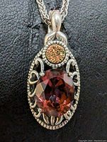 Close-up front view of pendant featuring oval faceted gemstone and smaller round druzy stone with detailed silver metalwork.