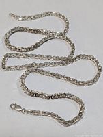 Full view of the sterling silver necklace laid out showing chain link texture and lobster clasp.