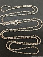 Sterling silver necklace laid out on a black surface showing chain detail and lobster clasp.