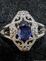 Close-up front view showing the sapphire and filigree setting with clear stones.