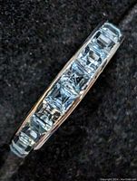 Side view close-up showing channel-set square cut light blue topaz stones along sterling silver band