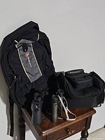 SwissGear backpack, two carry bags, and two sets of binoculars on wooden surface