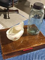 Gravy boat and glass canister on wooden box.