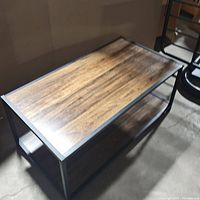 Angle view of the rectangular aluminum framed coffee table with wood finish top and shelf showing full table from above.