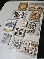 Photo showing multiple wooden stamp sets with floral and geometric patterns arranged on plastic trays.