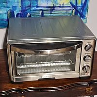Front view of stainless steel Cuisinart toaster oven broiler with glass door, wire rack inside, and control knobs on the right side.