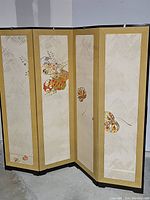 Full view of the four-panel room divider screen unfolded, showcasing floral designs on cream and gold bordered fabric panels.