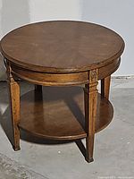 Vintage round wooden side table showing full view with top and lower shelf and carved leg details.