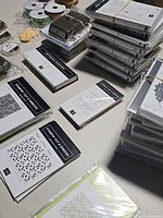 Wide view of stamp embossing folders and other paper crafting supplies stacked on a table.